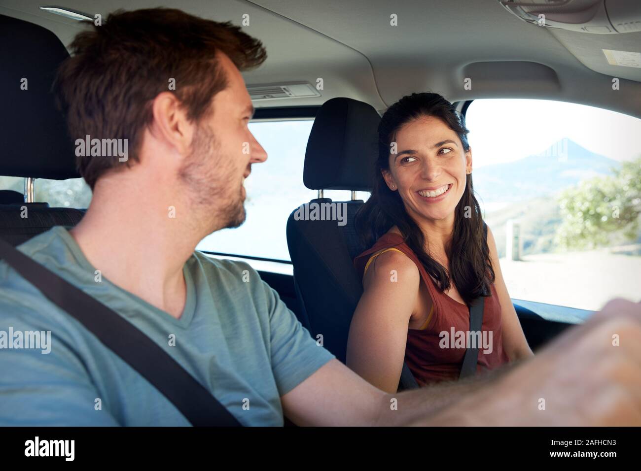 Happy Mid adult couple blanc roulant dans leur voiture, souriant à l'autre, Close up, side view Banque D'Images