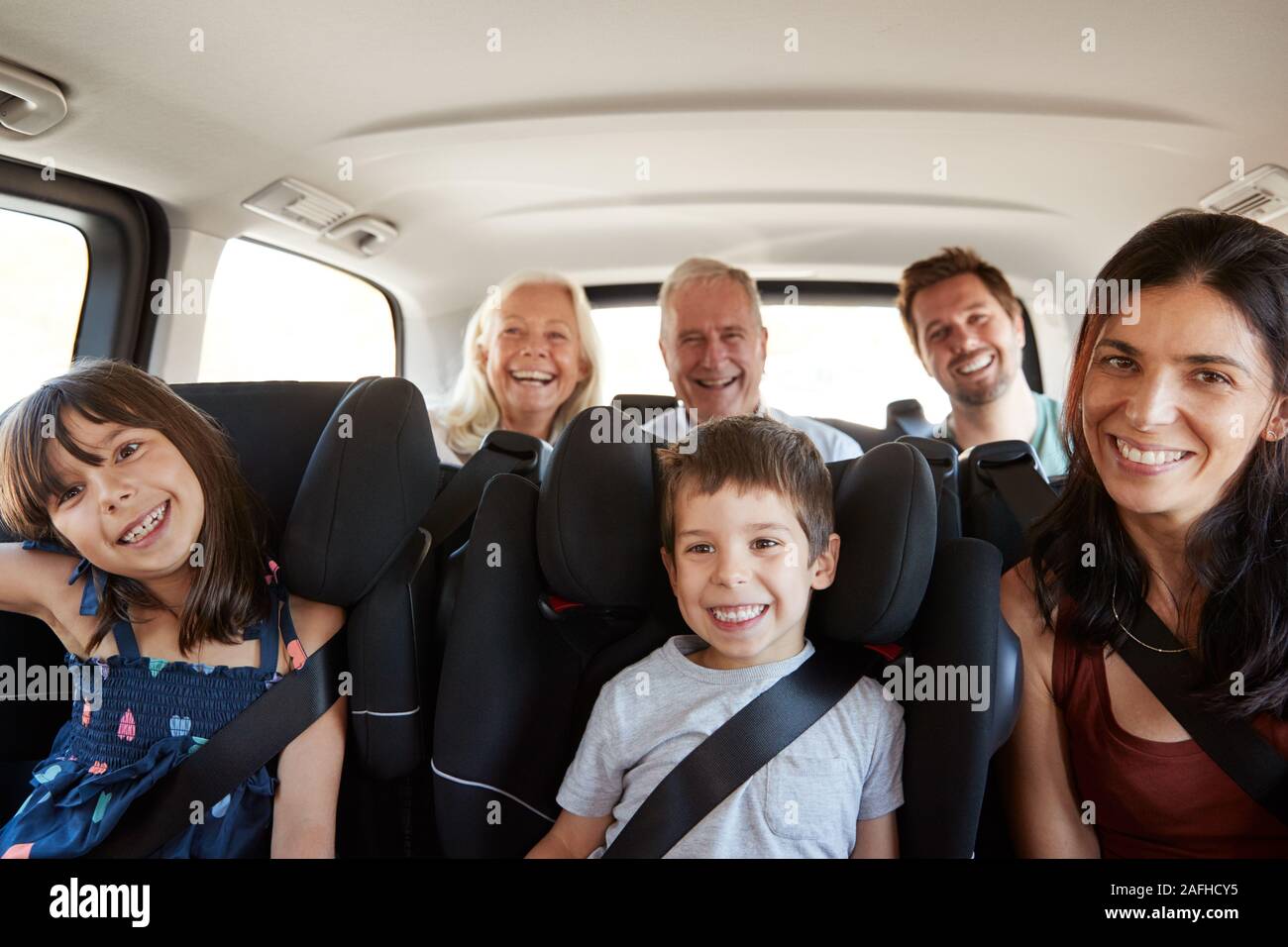 Trois générations de la famille blanc assis en deux rangées de sièges passagers dans une voiture, souriant à l'appareil photo Banque D'Images