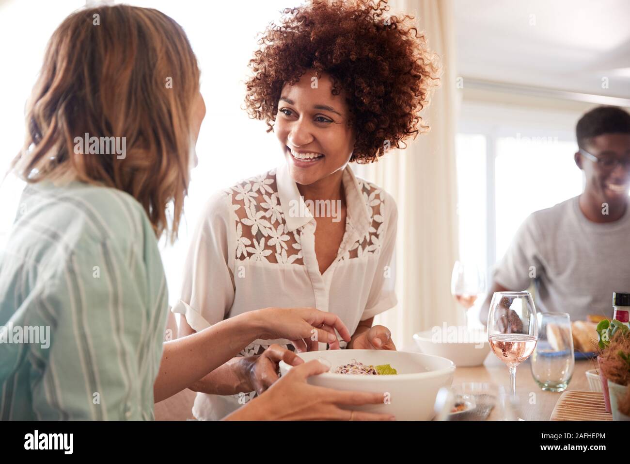 Deux copines à parler au millénaire table durant le repas avec des amis, Close up Banque D'Images