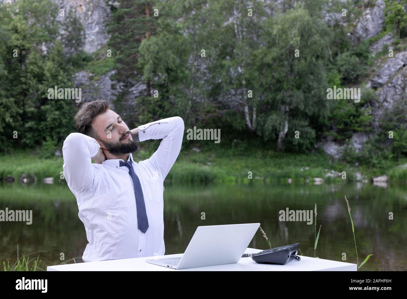Young male office worker masser son cou alors qu'il était assis dans un lieu de travail. Businessman sentiment douleur dans le cou après avoir siégé au bureau. Se sentir épuisé. Banque D'Images