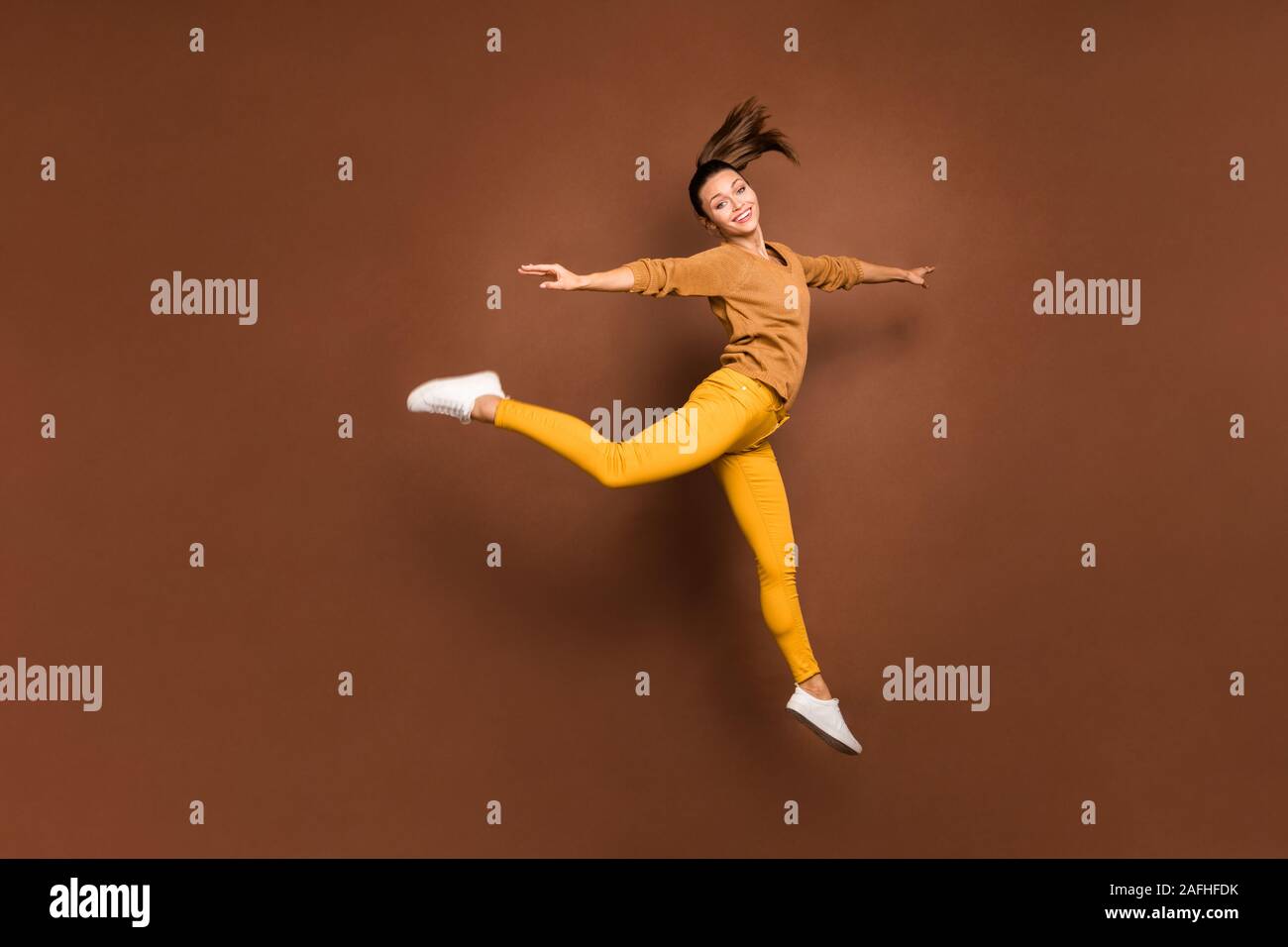 La taille du corps sur toute la longueur de la photo belle fille mignonne fascinant charme tournant sautant comme ballerine satisfait heureux isolé plus de brown Banque D'Images