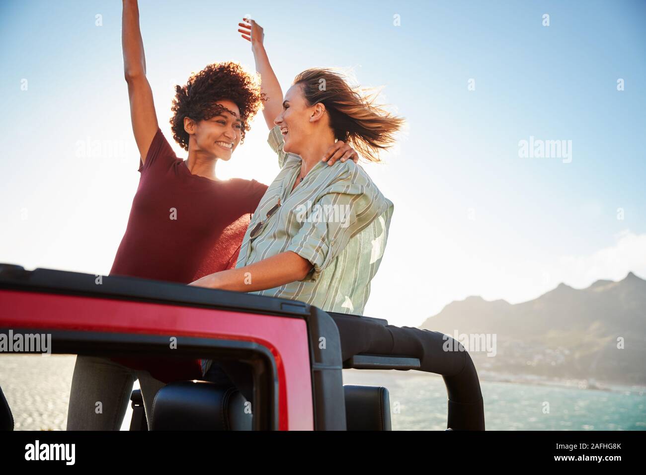 Deux amis de sexe féminin millénaire d'un voyage debout dans l'arrière d'une voiture à toit ouvert, Close up Banque D'Images