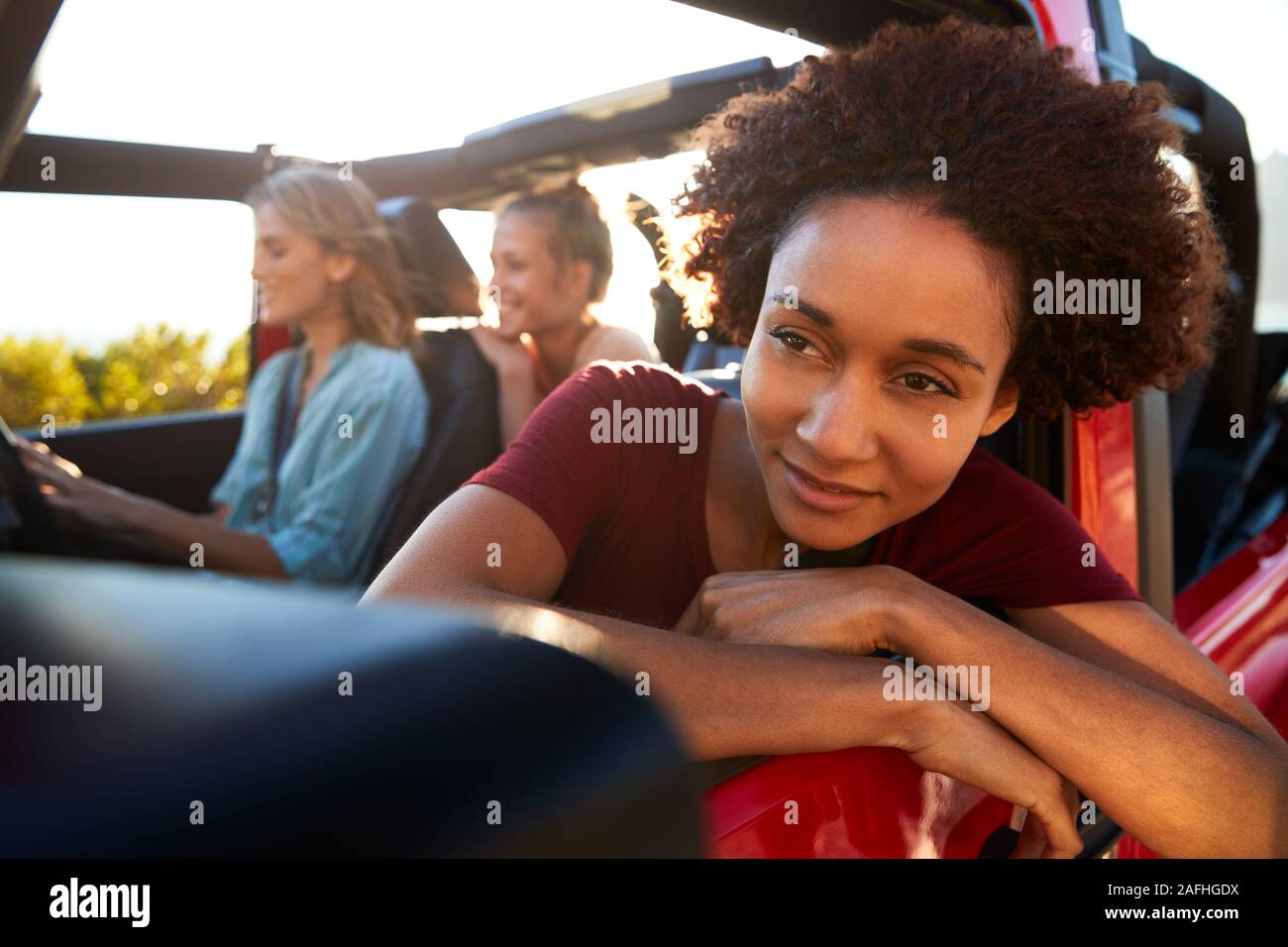 Millennial African American woman on road trip avec des amis, se penchant hors de la fenêtre de voiture, Close up Banque D'Images