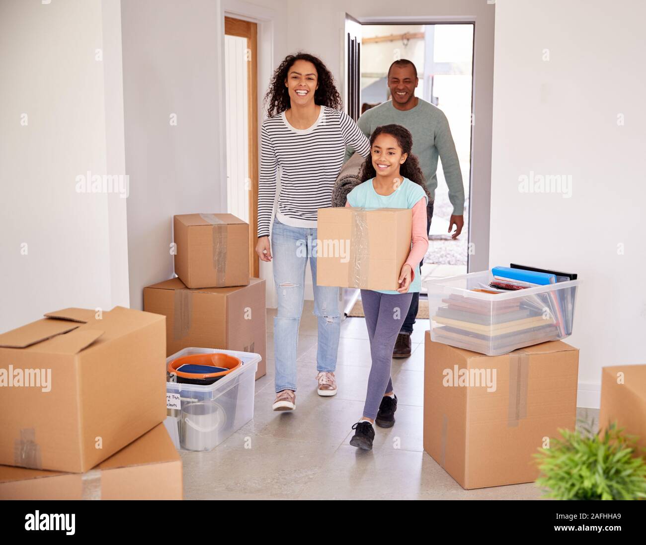 Smiling Family Carrying Boxes dans nouvelle maison le jour du déménagement Banque D'Images