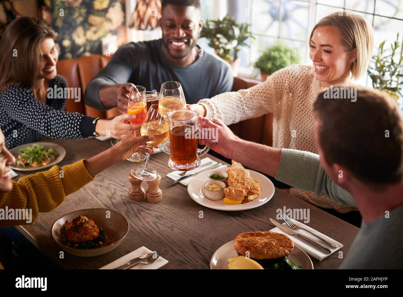 Réunion d'amis pour les repas au Pub Anglais traditionnel faisant toasts ensemble Banque D'Images
