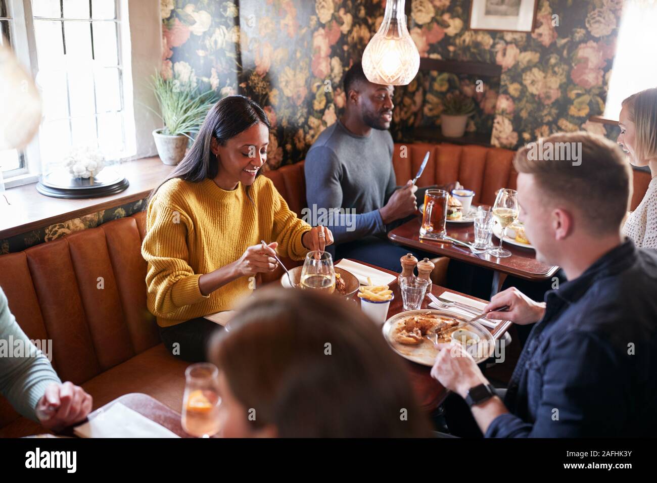 Groupe de personnes qui mangent au restaurant très animé d'un pub anglais traditionnel Banque D'Images