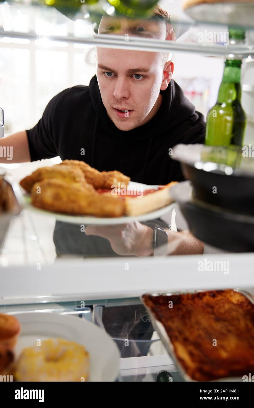 À la vue de l'intérieur du réfrigérateur rempli d'aliments à emporter malsain que l'homme ouvre la porte Banque D'Images