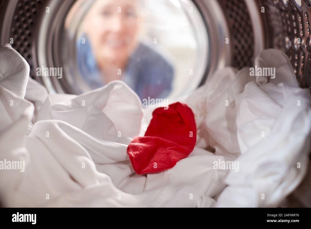 Femme à l'intérieur d'un lave-linge avec Chaussette rouge blanc mélangé avec une laverie Banque D'Images