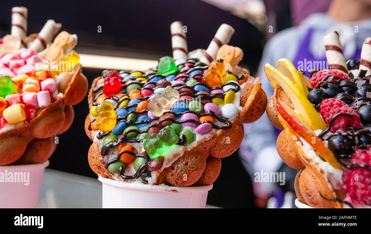 Gaufres bulle avec les framboises, chocolat et guimauve dans du papier blanc tasses sont vendues sur cuisine ouverte food festival événement. Gaufres de Hong Kong. Concep Banque D'Images