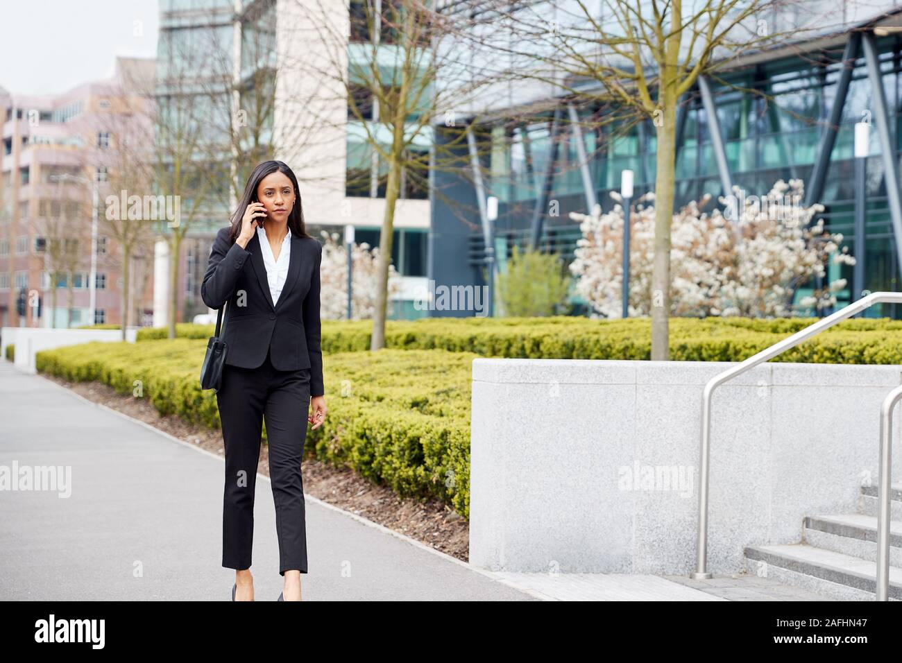 Se rendre au travail Businesswoman Talking On Mobile Phone hors Immeuble de bureaux modernes Banque D'Images