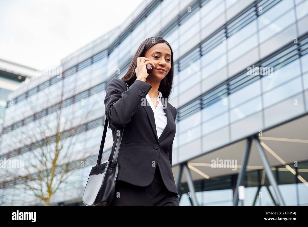Se rendre au travail Businesswoman Talking On Mobile Phone hors Immeuble de bureaux modernes Banque D'Images