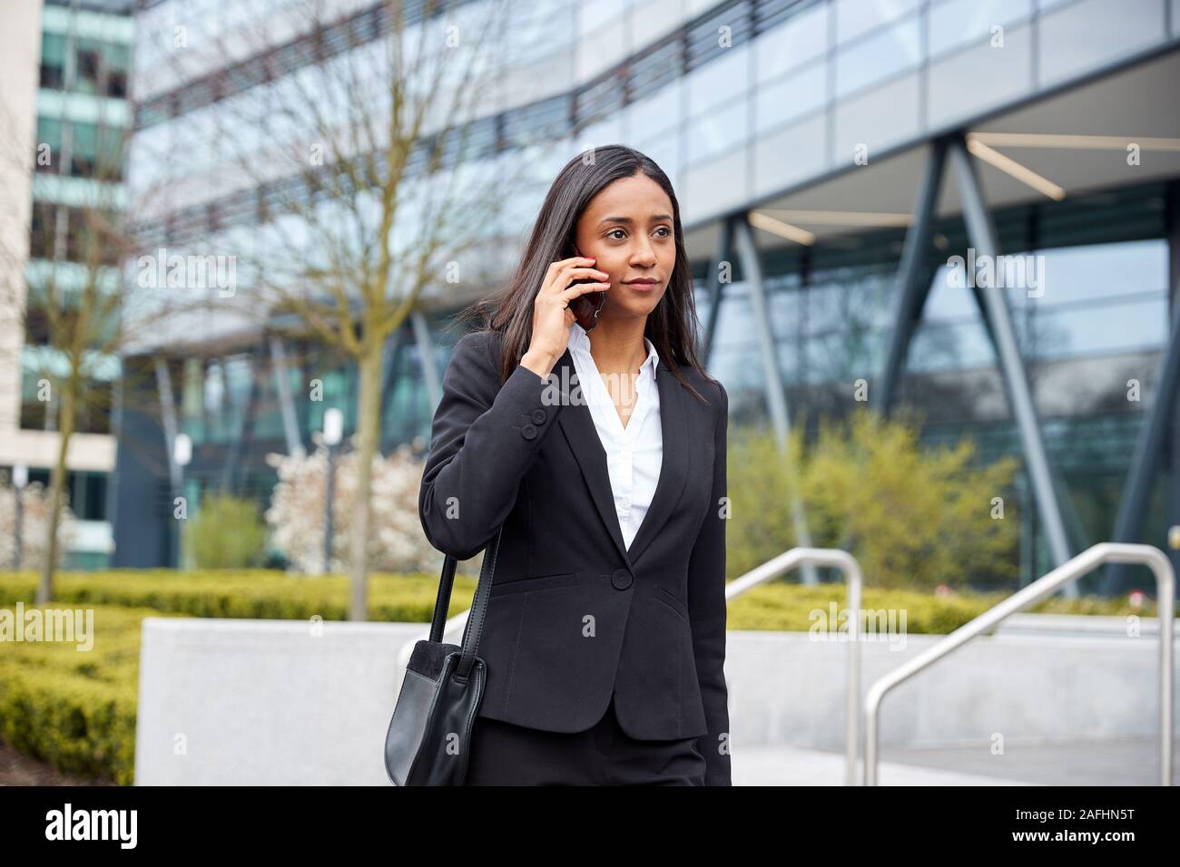 Se rendre au travail Businesswoman Talking On Mobile Phone hors Immeuble de bureaux modernes Banque D'Images
