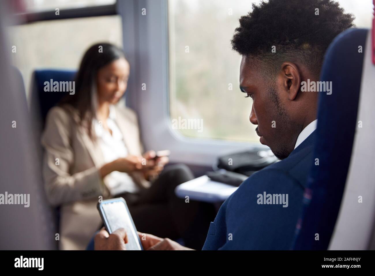 Les passagers assis dans le train pour se rendre à son travail à la recherche de téléphones mobiles Banque D'Images