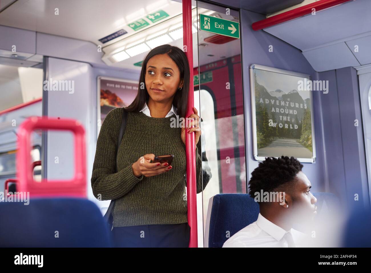 Femme Debout de passagers par portes en train à l'aide de Mobile Phone Banque D'Images