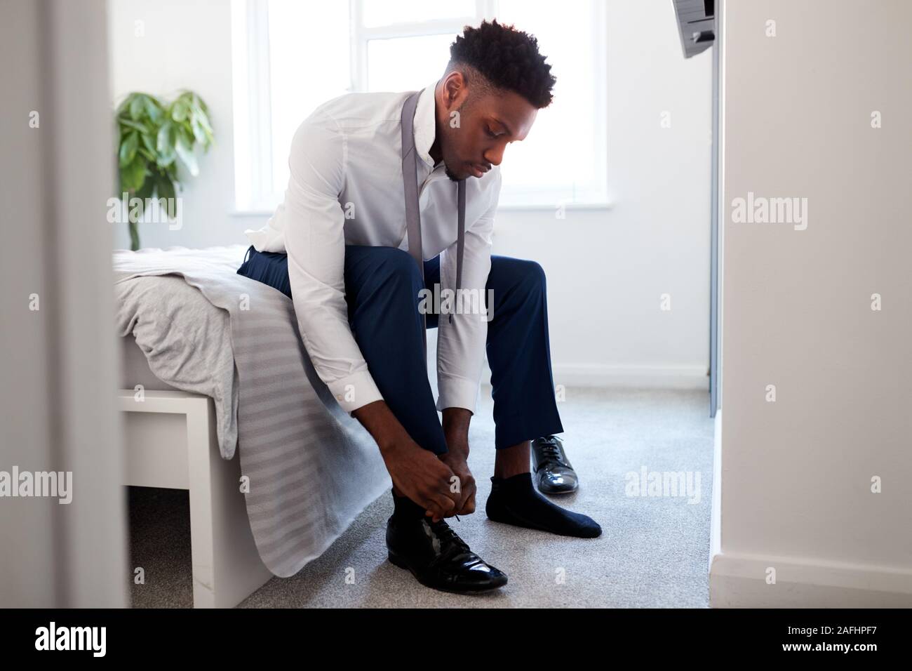 Businessman At home sitting on Bed mise sur les chaussures avant de quitter pour le travail Banque D'Images