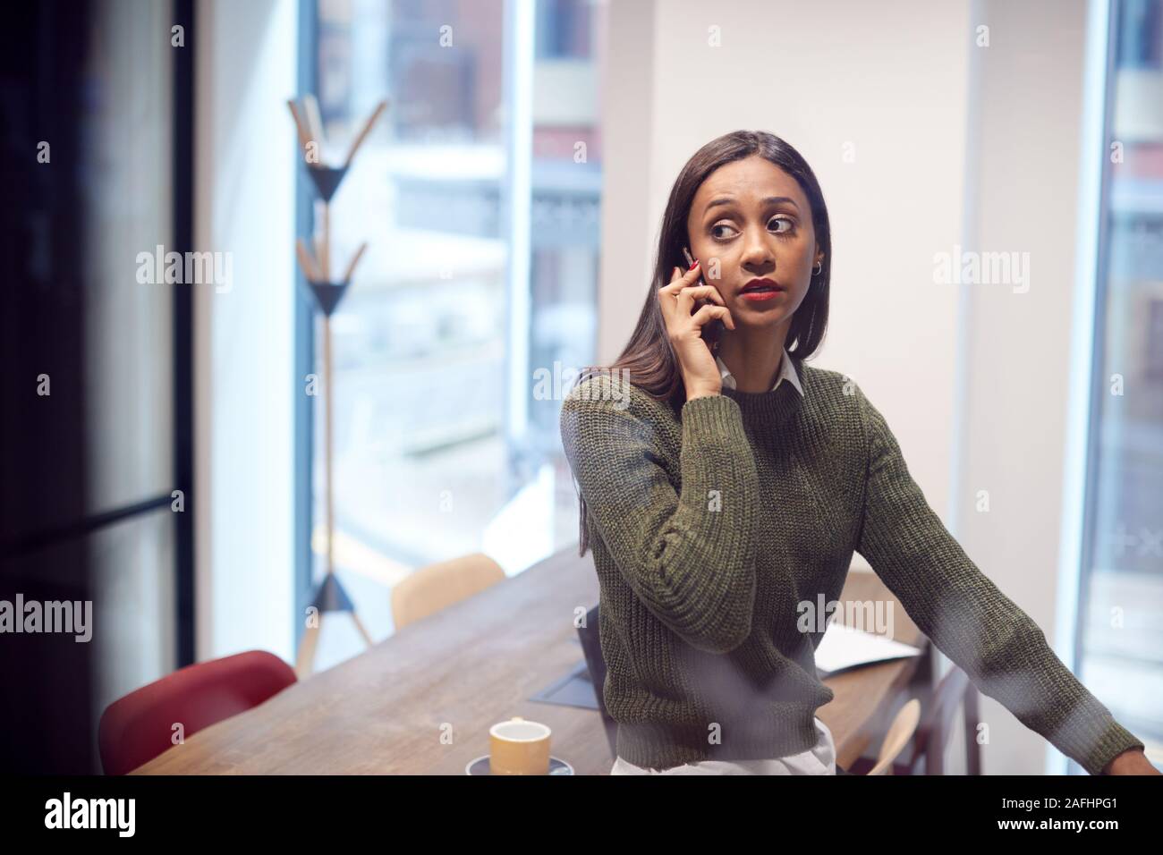 Businesswoman Sitting on Desk in Meeting Room Talking On Mobile Phone Banque D'Images