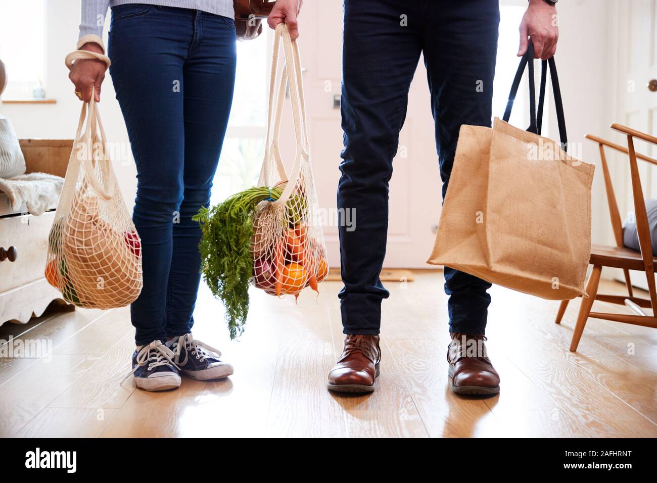 Close Up of Couple au retour de voyage de shopping à porter des sacs d'épicerie en plastique dans des sacs gratuits Banque D'Images