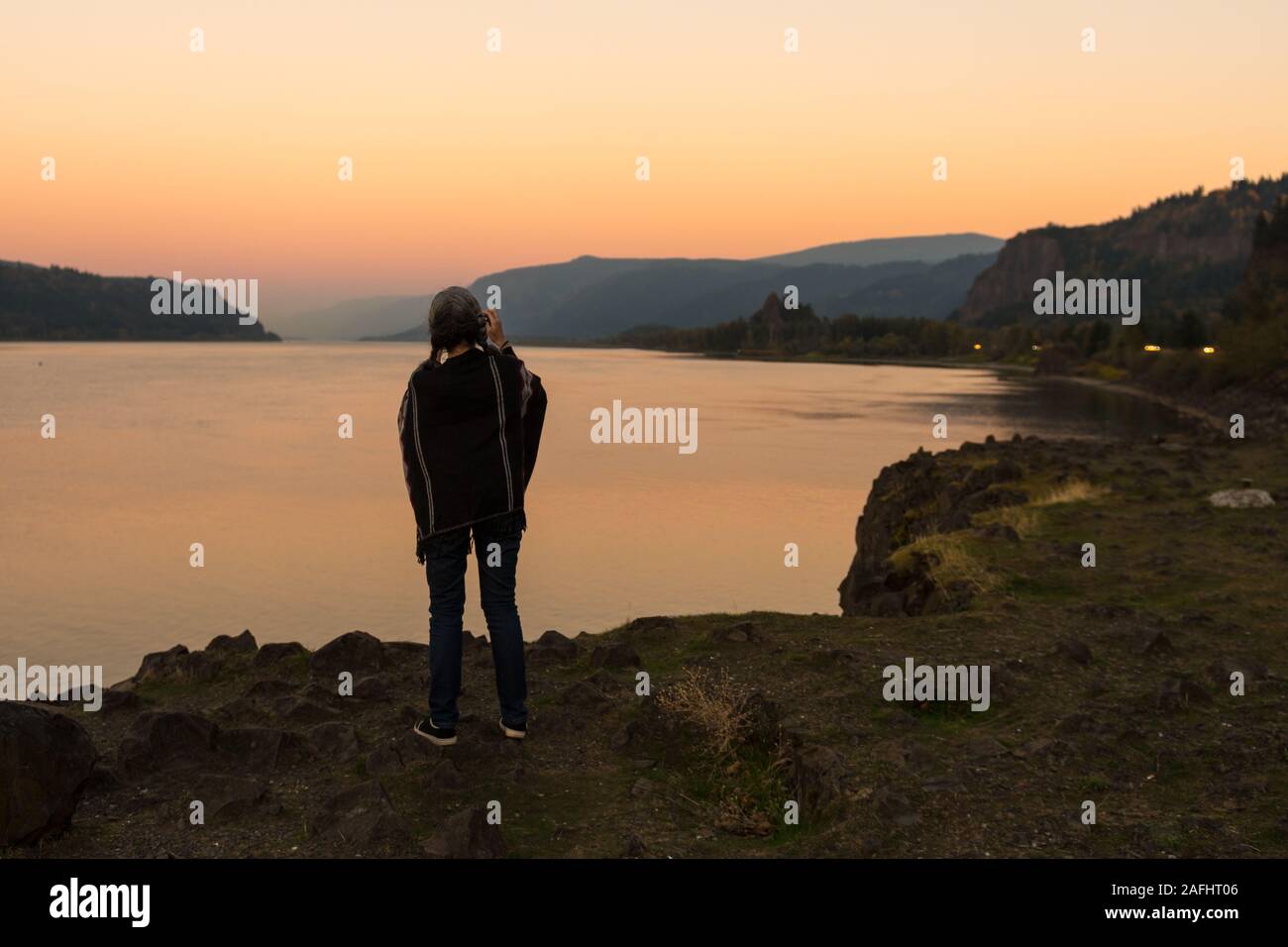 Jeune femme avec poncho sur le coucher du soleil prend des photos à la Corbett lookout sur le fleuve Columbia, New York Banque D'Images