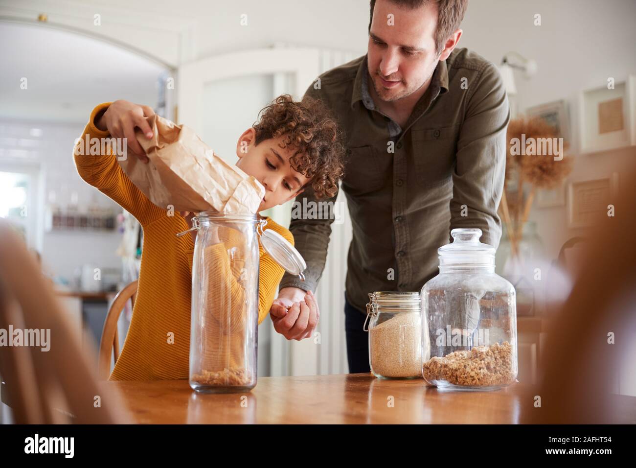 Père Fils aidant à remplir les contenants d'aliments à domicile à l'aide de l'emballage des déchets Zéro Banque D'Images
