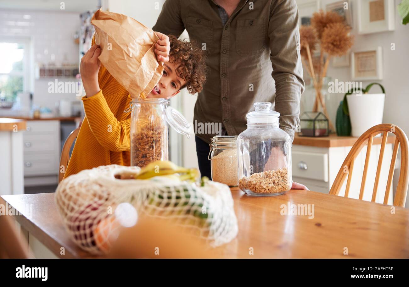 Père Fils aidant à remplir les contenants d'aliments à domicile à l'aide de l'emballage des déchets Zéro Banque D'Images