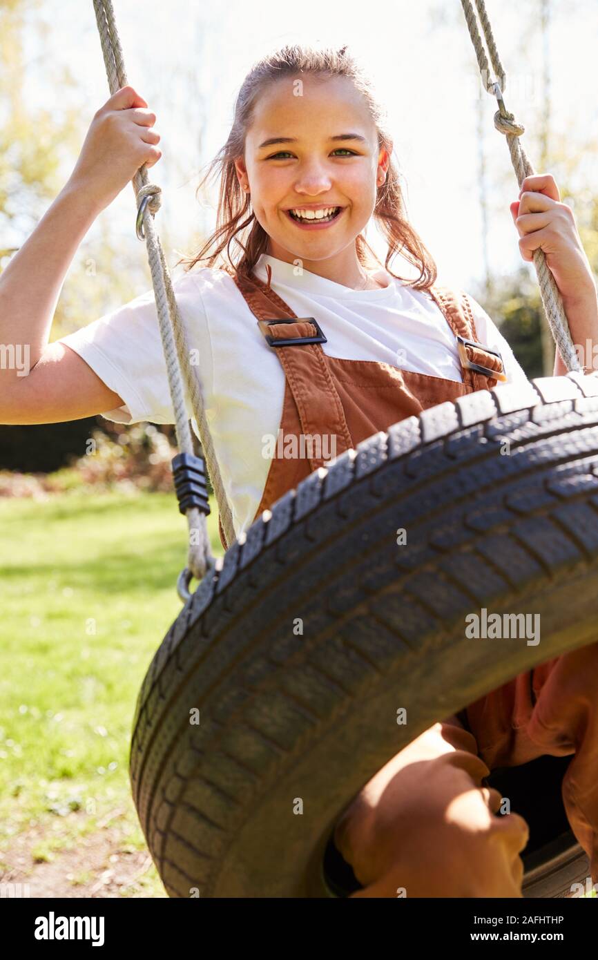 Portrait de jeune fille s'amusant sur balançoire pneu en jardin à la maison Banque D'Images