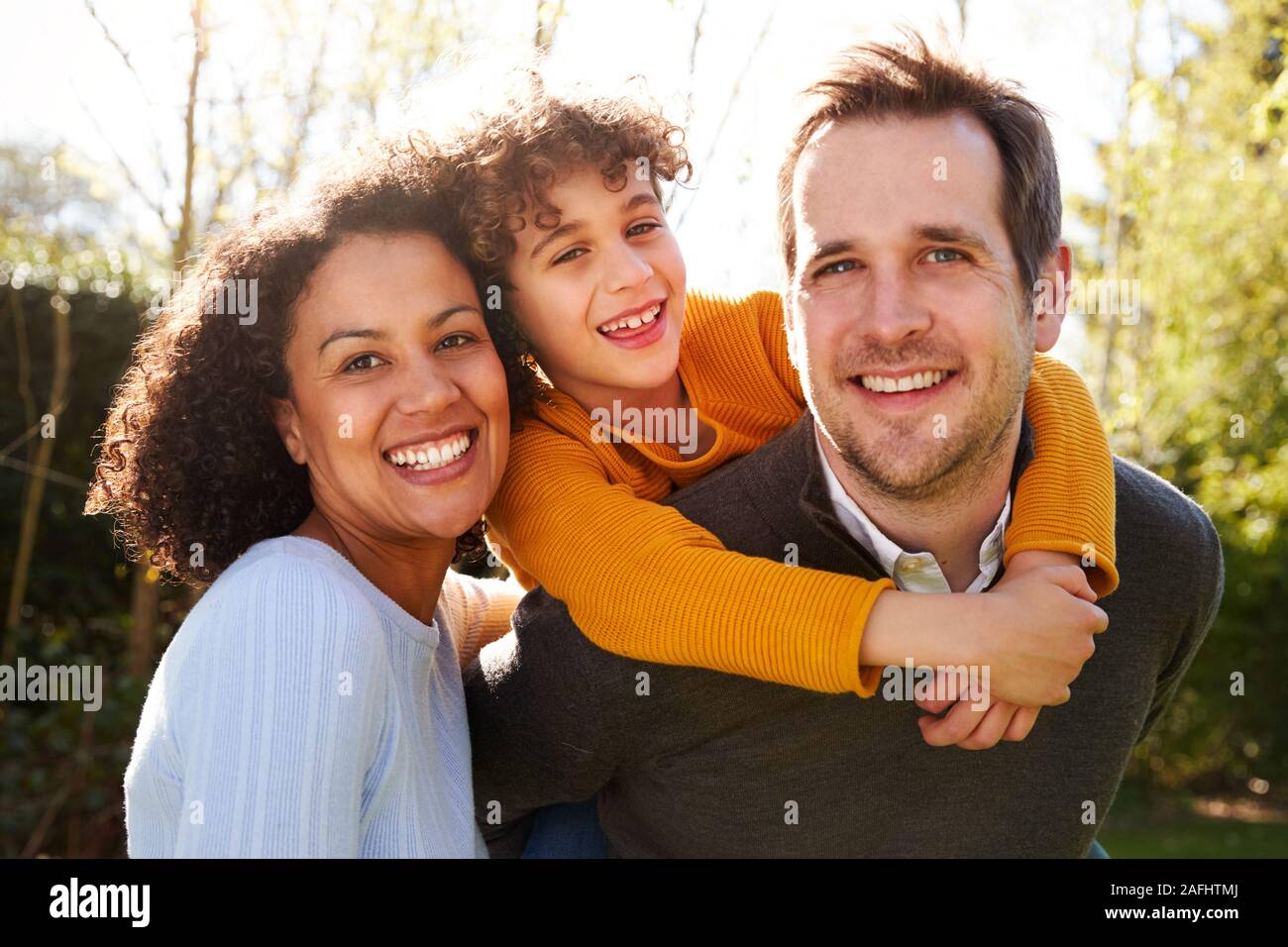 Outdoor Portrait Of Smiling Family in garden at home contre Sun Torchage Banque D'Images