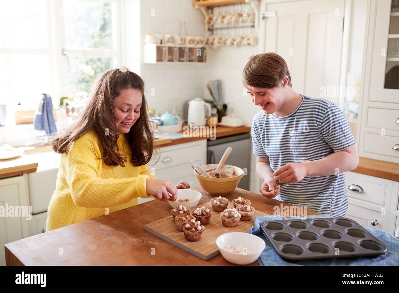 Les jeunes Trisomie Couple Decorating Cupcakes fait maison avec des guimauves dans la cuisine à la maison Banque D'Images