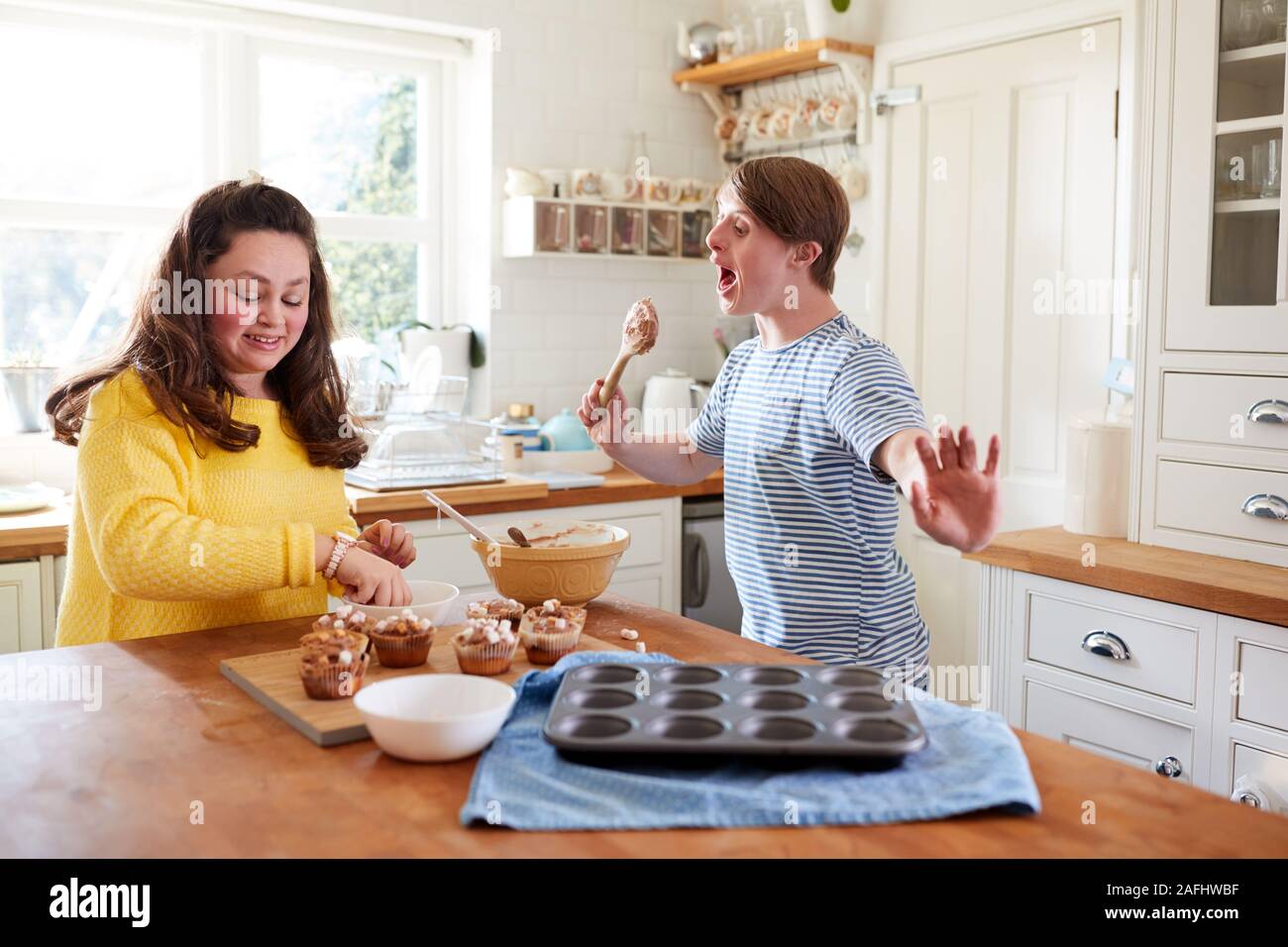 Les jeunes Trisomie Couple Decorating Cupcakes fait maison avec des guimauves dans la cuisine à la maison Banque D'Images