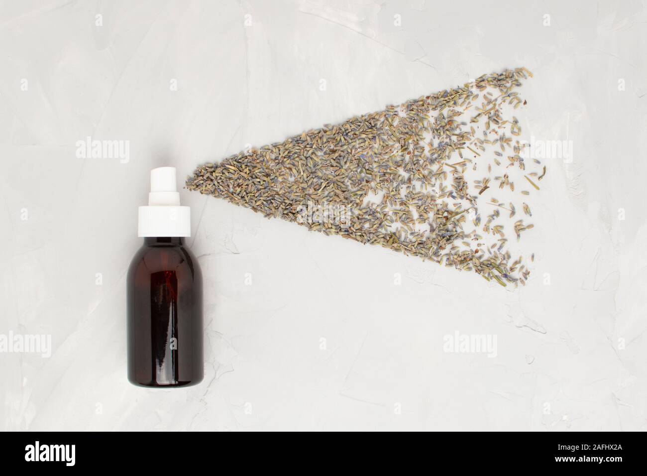 Cosmétique transparent verre ambre vaporisateur sur un fond blanc. Fleurs de Lavande comme les petites gouttelettes de nuage de pulvérisation à partir d'une télévision.. Banque D'Images