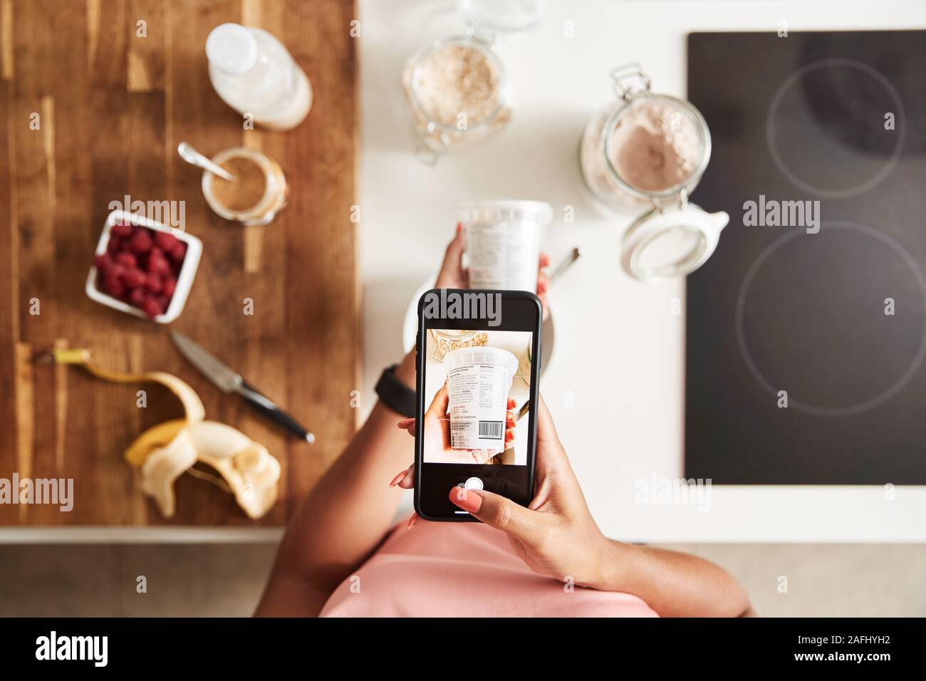 Femme portant des vêtements Fitness Scanning QR code sur l'emballage des aliments à trouver de l'information nutritionnelle Banque D'Images