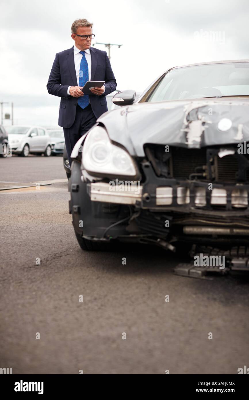 Sinistres Assurance mâle avec tablette numérique l'inspection des dommages au moteur de voiture Accident Banque D'Images
