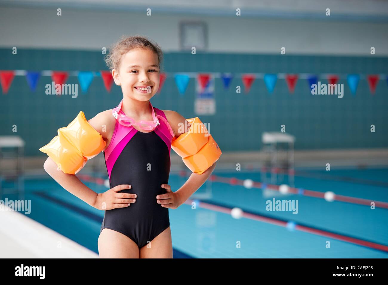 Portrait de jeune fille portant des brassards en bord de piscine prête pour la leçon Banque D'Images