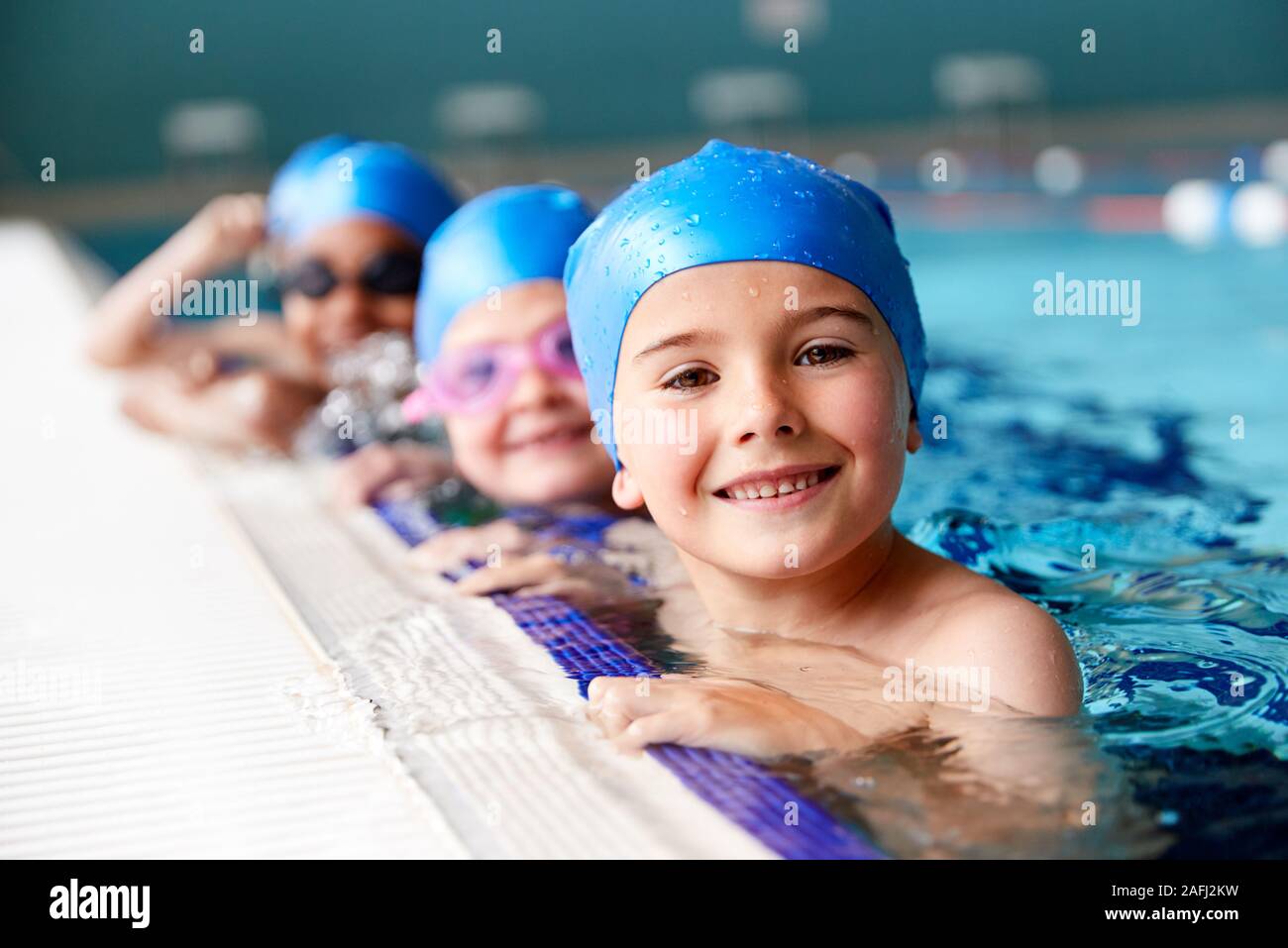 Portrait des enfants dans l'eau à bord de piscine en attente de leçon de natation Banque D'Images