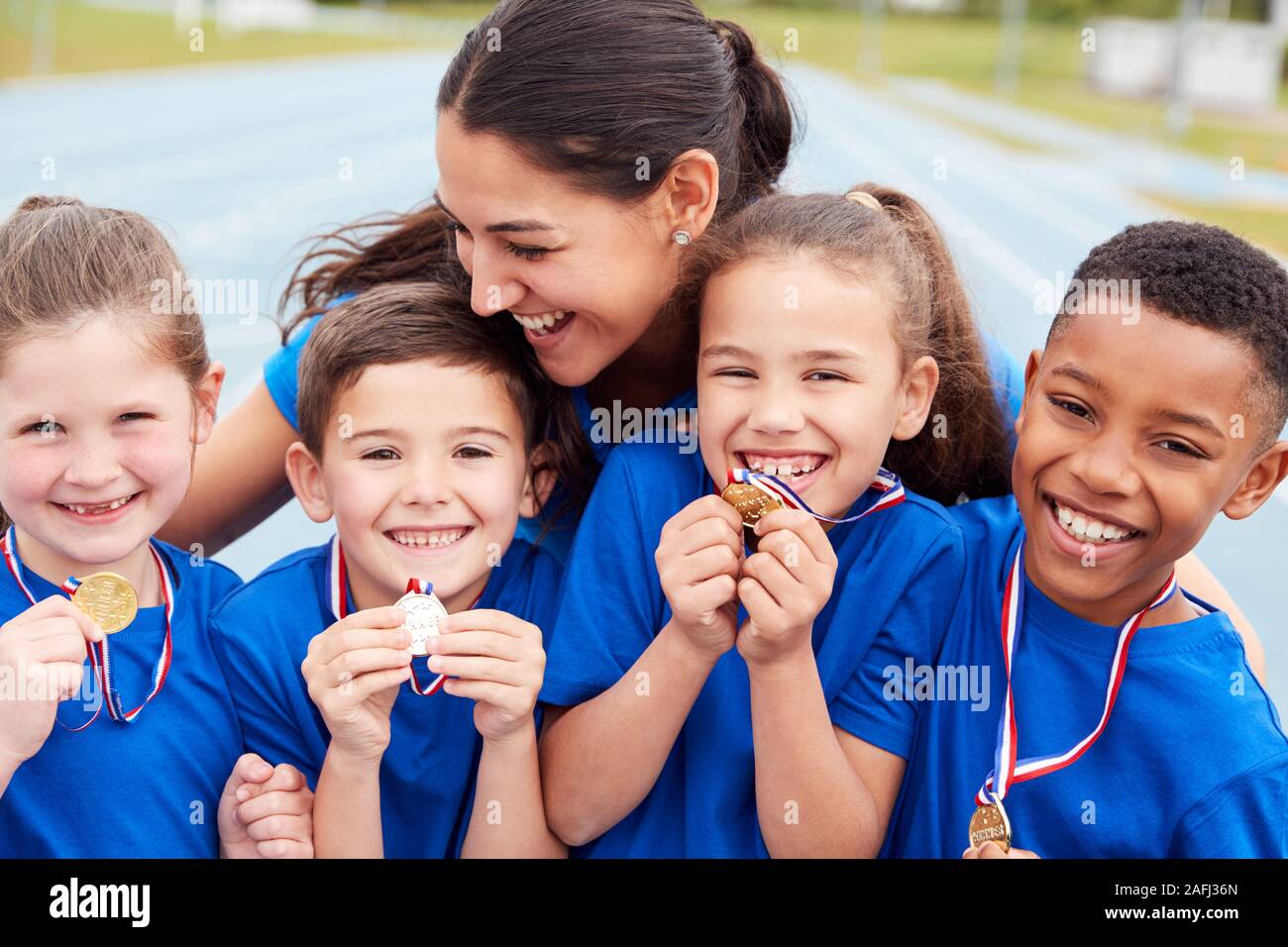 Les enfants avec entraîneur féminin montrant outre de gagnants de médailles sur la Journée des sports Banque D'Images