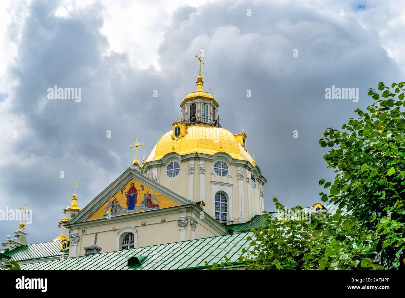 La partie supérieure de la superbe cathédrale de la Dormition orthodoxe Baroque de Pochayiv Lavra en Ukraine. Toit et dôme doré avec une croix dans le ciel nuageux dar Banque D'Images