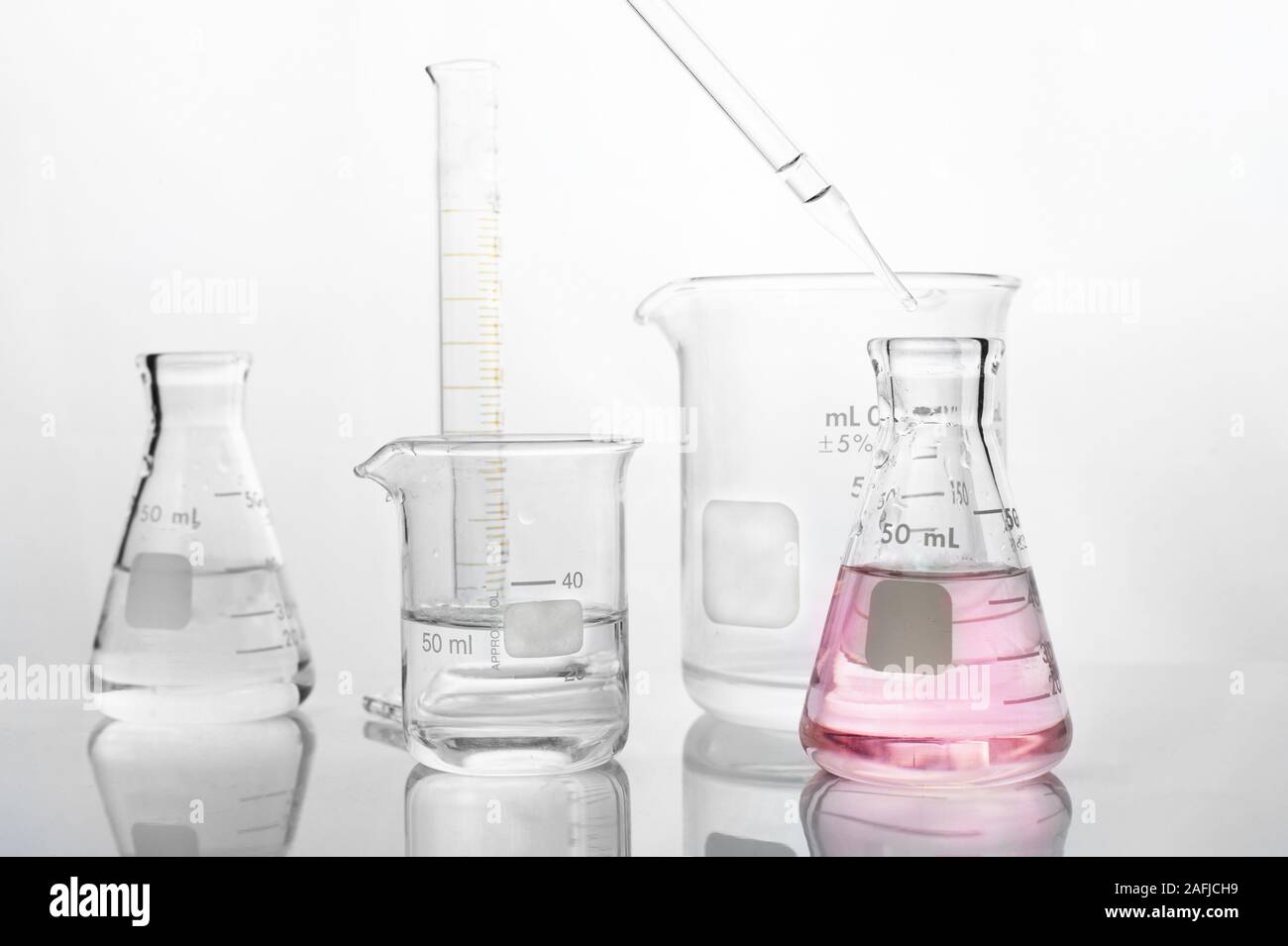 Bécher en verre bouteille flacon compte-gouttes avec de l'eau et de chimie science laboratory fond blanc Banque D'Images