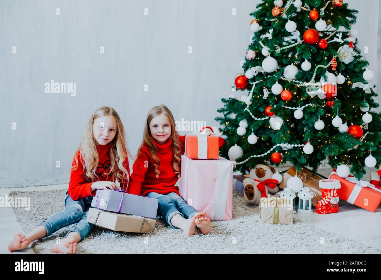 Deux petites filles blonde en robe rouge à cadeaux de noël vacances du Nouvel an Banque D'Images