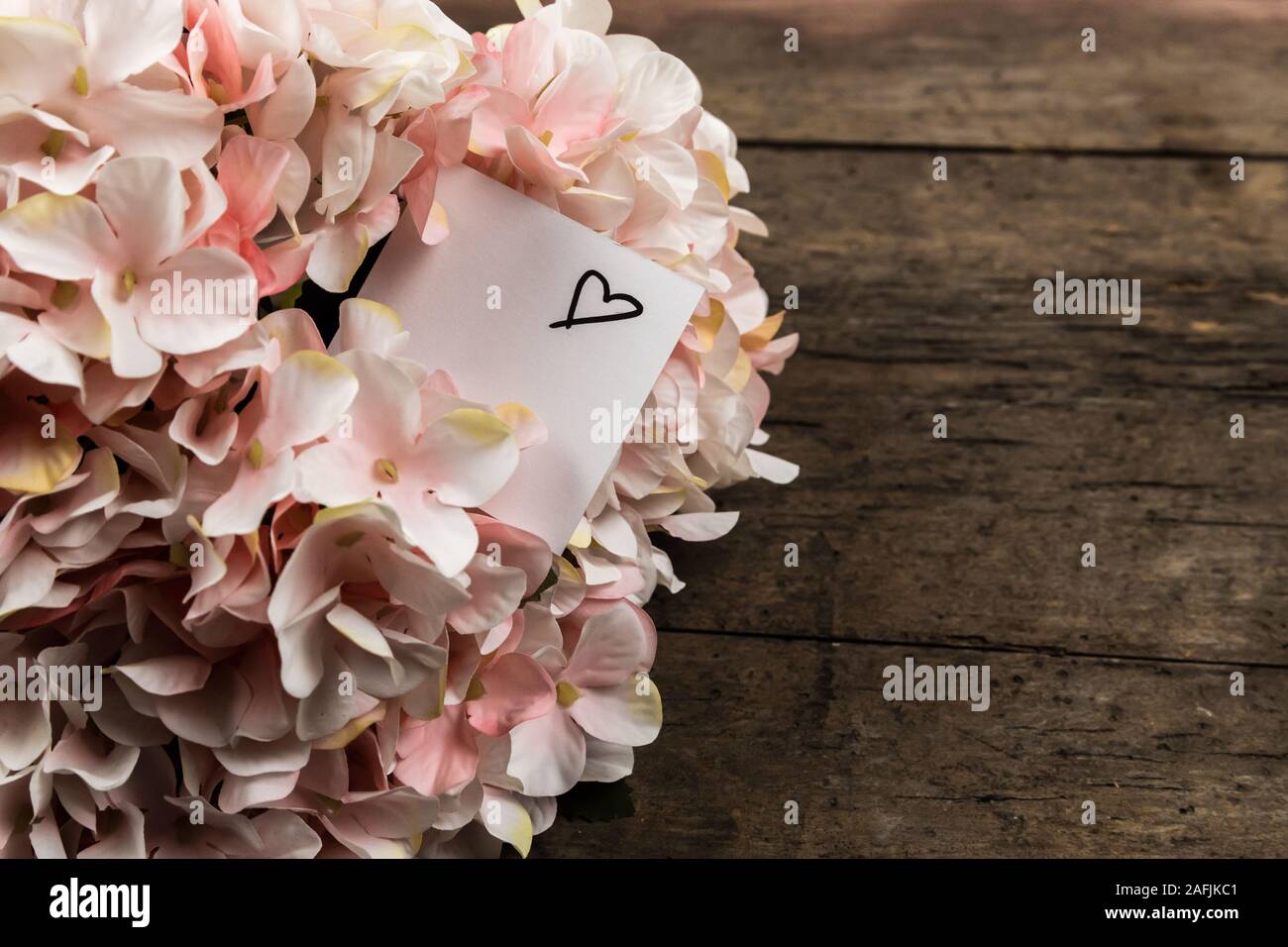Hortensia rose pastel fleurs et un morceau de papier sur fond de bois. L'espace de copie pour le texte. Banque D'Images
