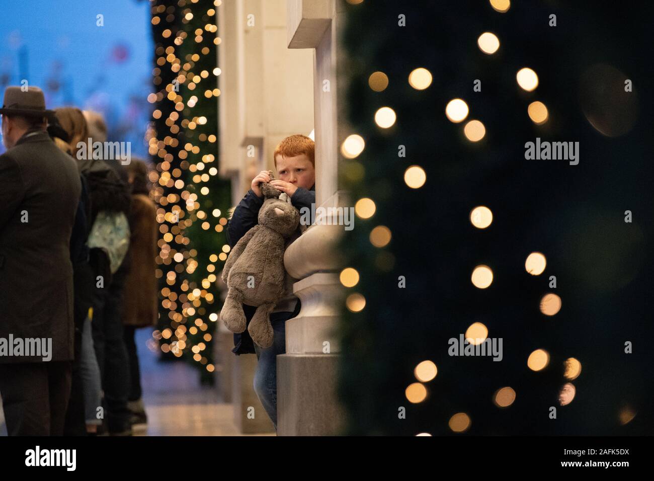 Petit garçon cheveux gingembre tenant un grand soft toy bunny en dehors de Selfridges. Lumières de Noël et décorations dans l'arrière-plan. Londres Banque D'Images