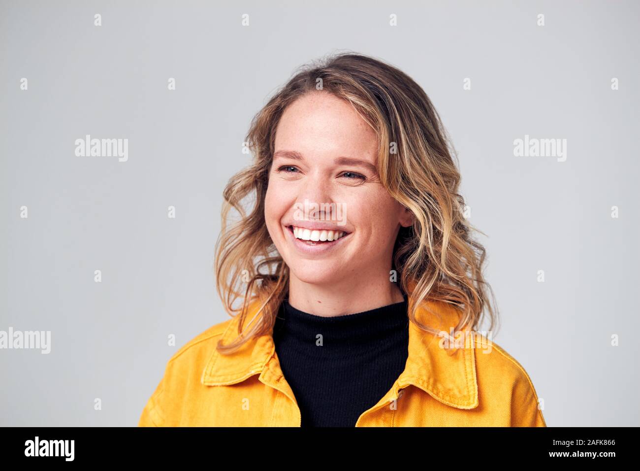 Studio Portrait Of Happy Young Woman Smiling positif hors caméra Banque D'Images