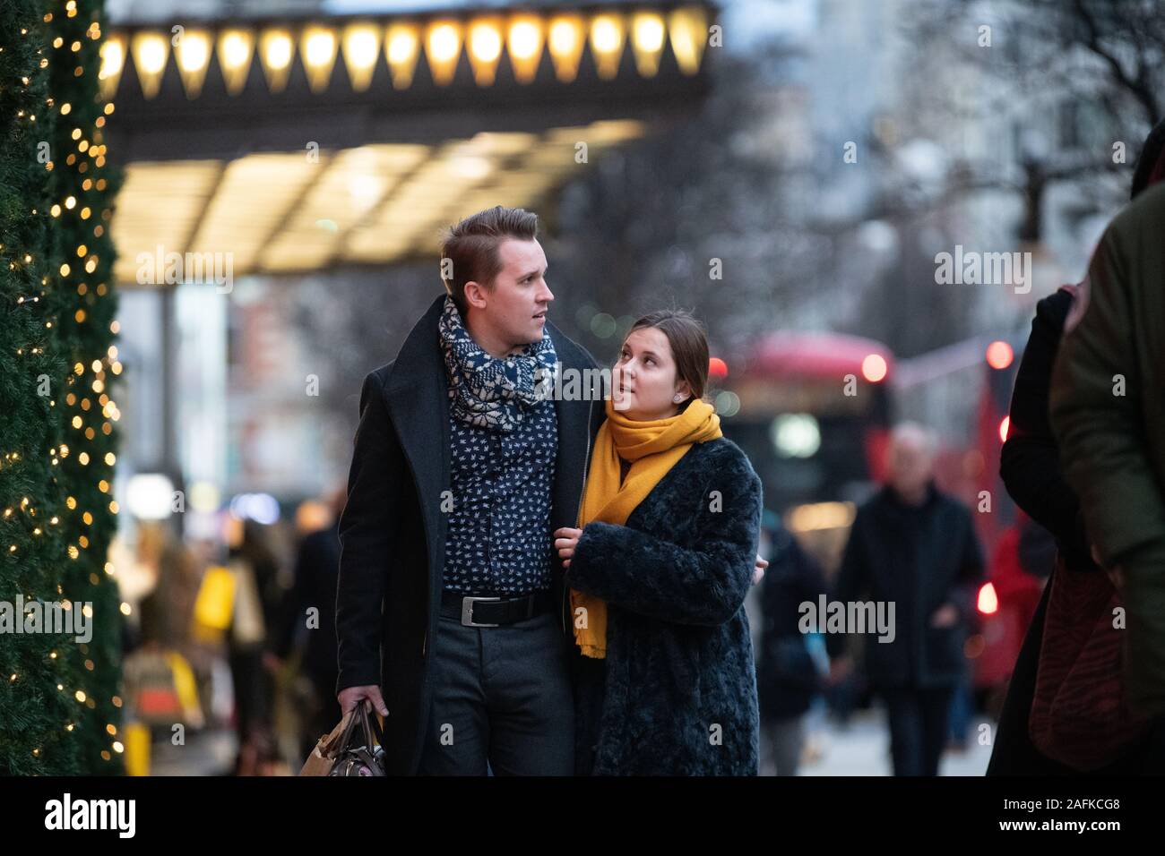 Un couple en train de marcher et de parler en dehors de Selfridges, Oxford Street, Londres. L'impression de Noël et les lumières à l'arrière-plan et de premier plan Banque D'Images