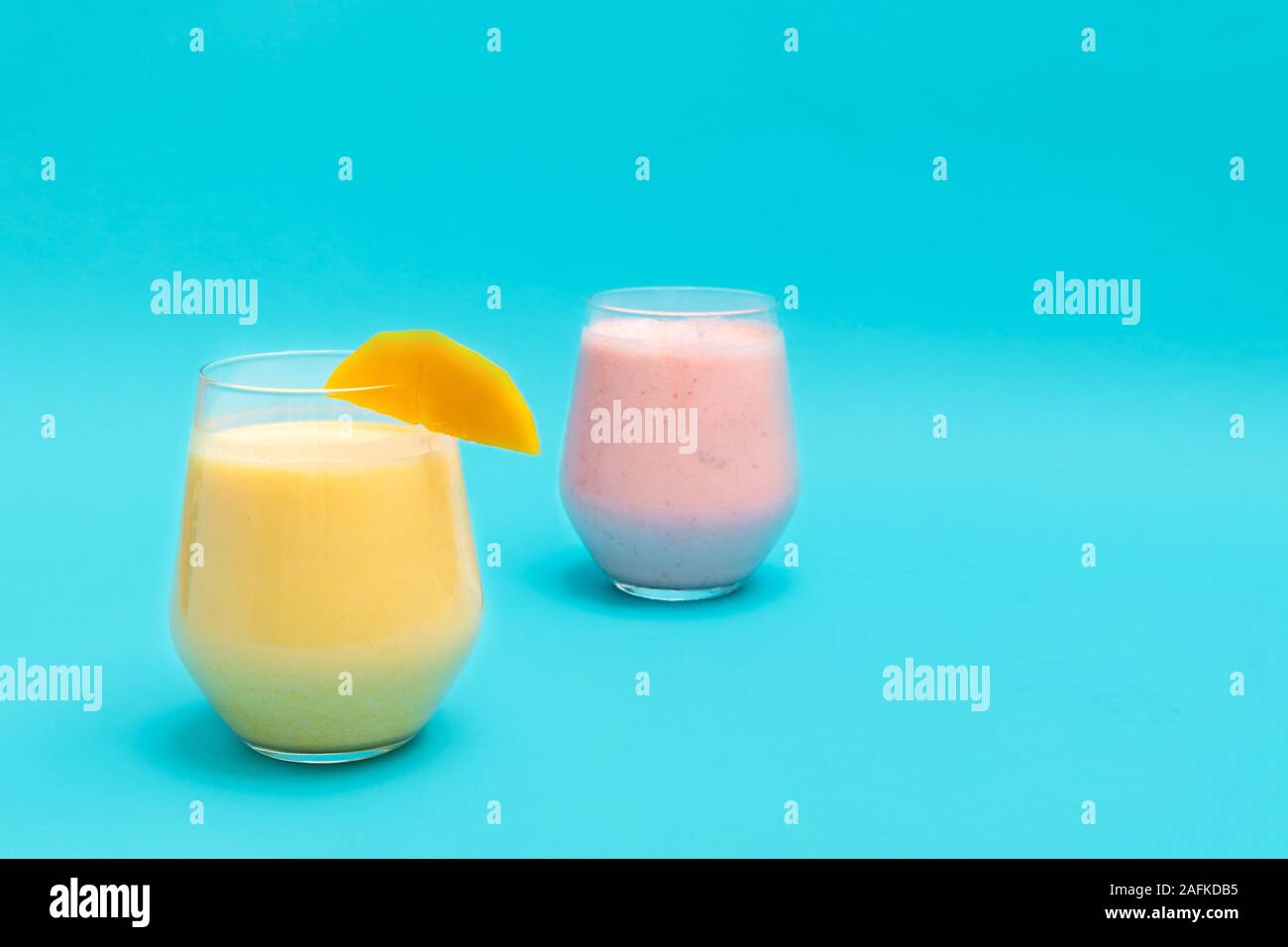 Lassi Lassi à la mangue et à la fraise en boissons tasses en verre sur fond bleu Banque D'Images