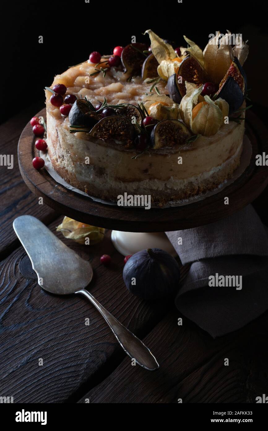 Gâteau au fromage avec dates et physalis sur un stand avec une serviette et une cuillère à la verticale Banque D'Images