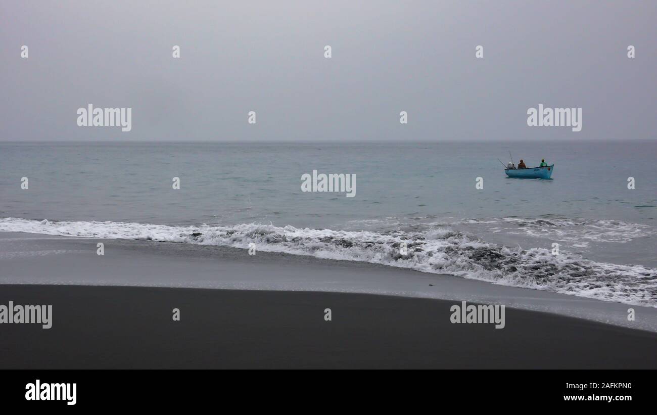 Sao Filipe / Fogo, Cap-Vert - 16. Novembre, 2019 : African pêcheur dans un esquif en bois la pêche sur la côte de sable de lave noire de l'île Fogo au Cap Ve Banque D'Images