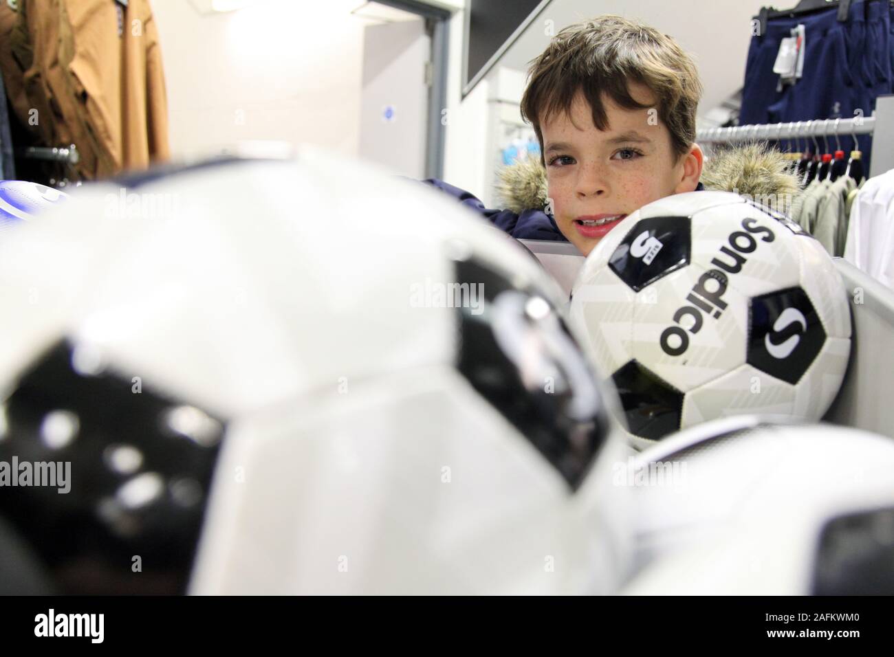 Un monsieur jeune garçon regarde au-dessus d'un rack de Sondico en ballons de sport JD, 2019 Banque D'Images