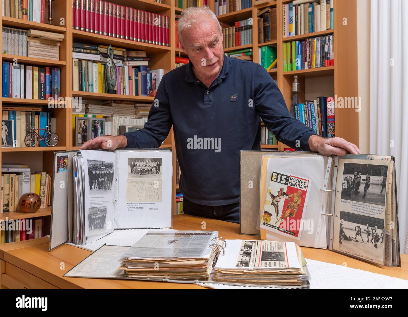 Dresde, Allemagne. Dec 16, 2019. Karl-Heinz Domschke, ancien joueur de hockey sur glace de la RDA, se tient à la maison avec des souvenirs de son étude. Il est en charge de la chronique des sports de glace en Dresde. Domschke, né en 1953, a joué pour Dresdner Eishockey-Vereine et l'équipe nationale de la RDA et recueille tout pour le hockey sur glace. Credit : Matthias Rietschel/dpa-Zentralbild/ZB/dpa/Alamy Live News Banque D'Images