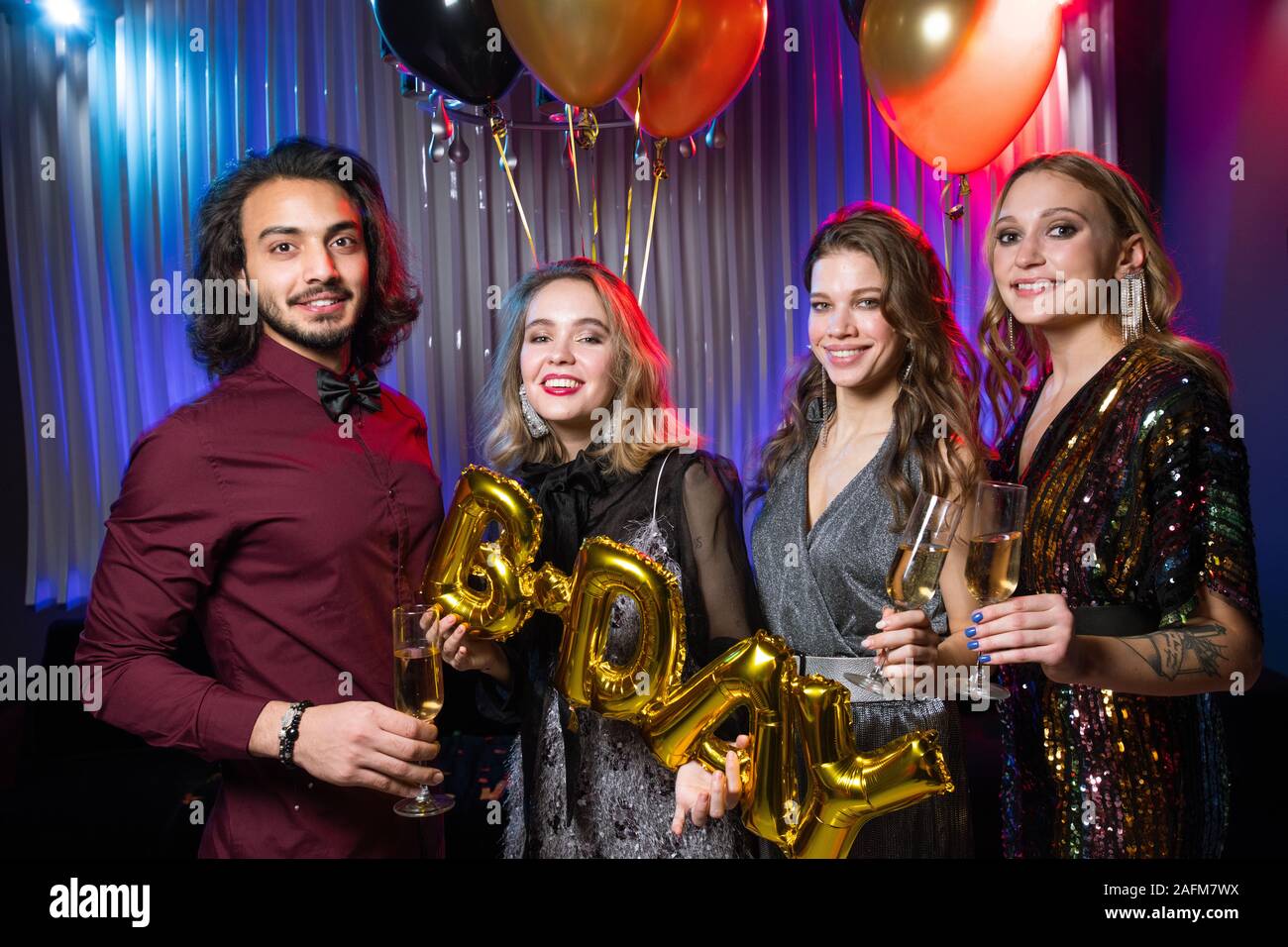 Trois filles heureuse et young man holding flutes de champagne et des ballons Banque D'Images