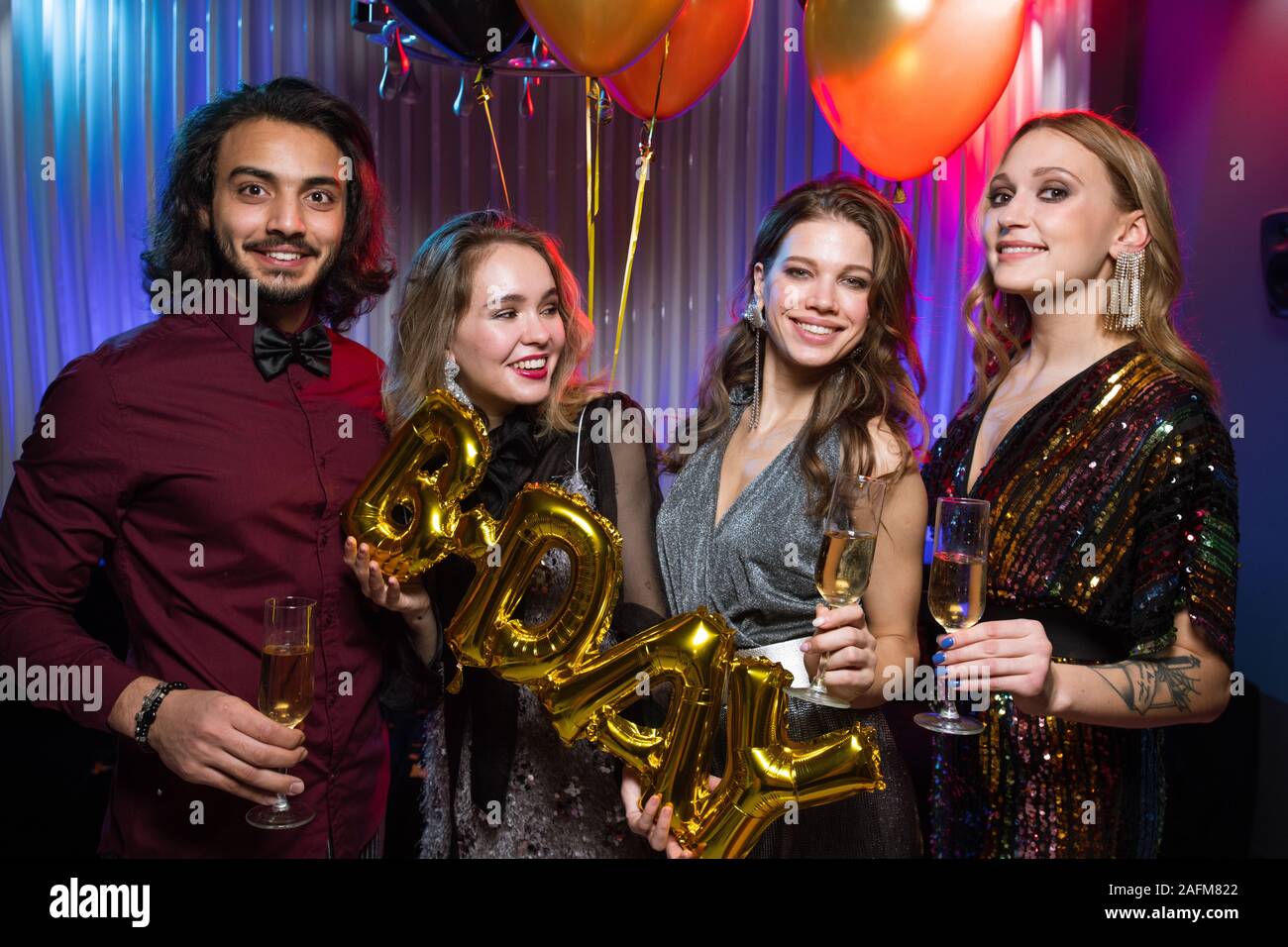 Les filles et les jeunes gais homme élégant holding flutes de champagne et des ballons Banque D'Images