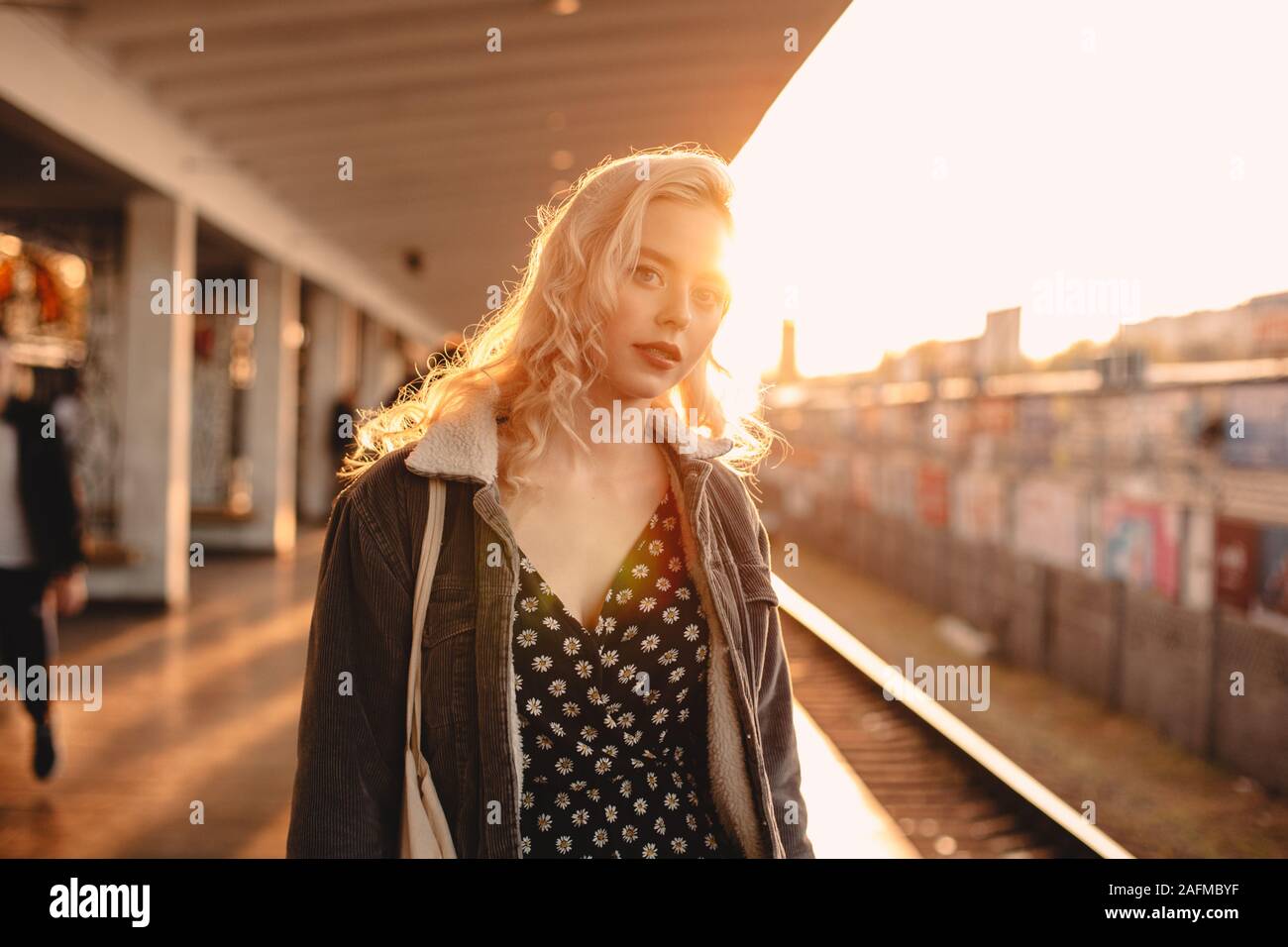 Jeune femme en attente de train à la station de métro au coucher du soleil Banque D'Images