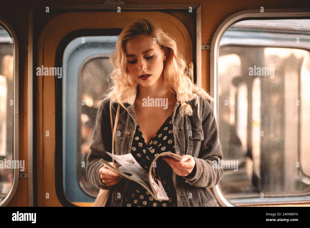 Young woman reading magazine pendant un voyage en train de métro Banque D'Images